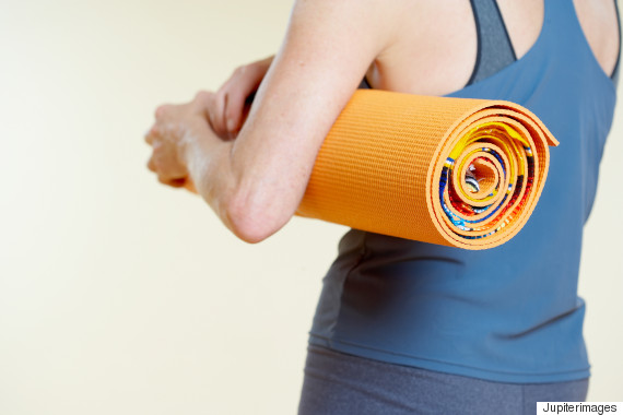 Woman with rolled yoga mat